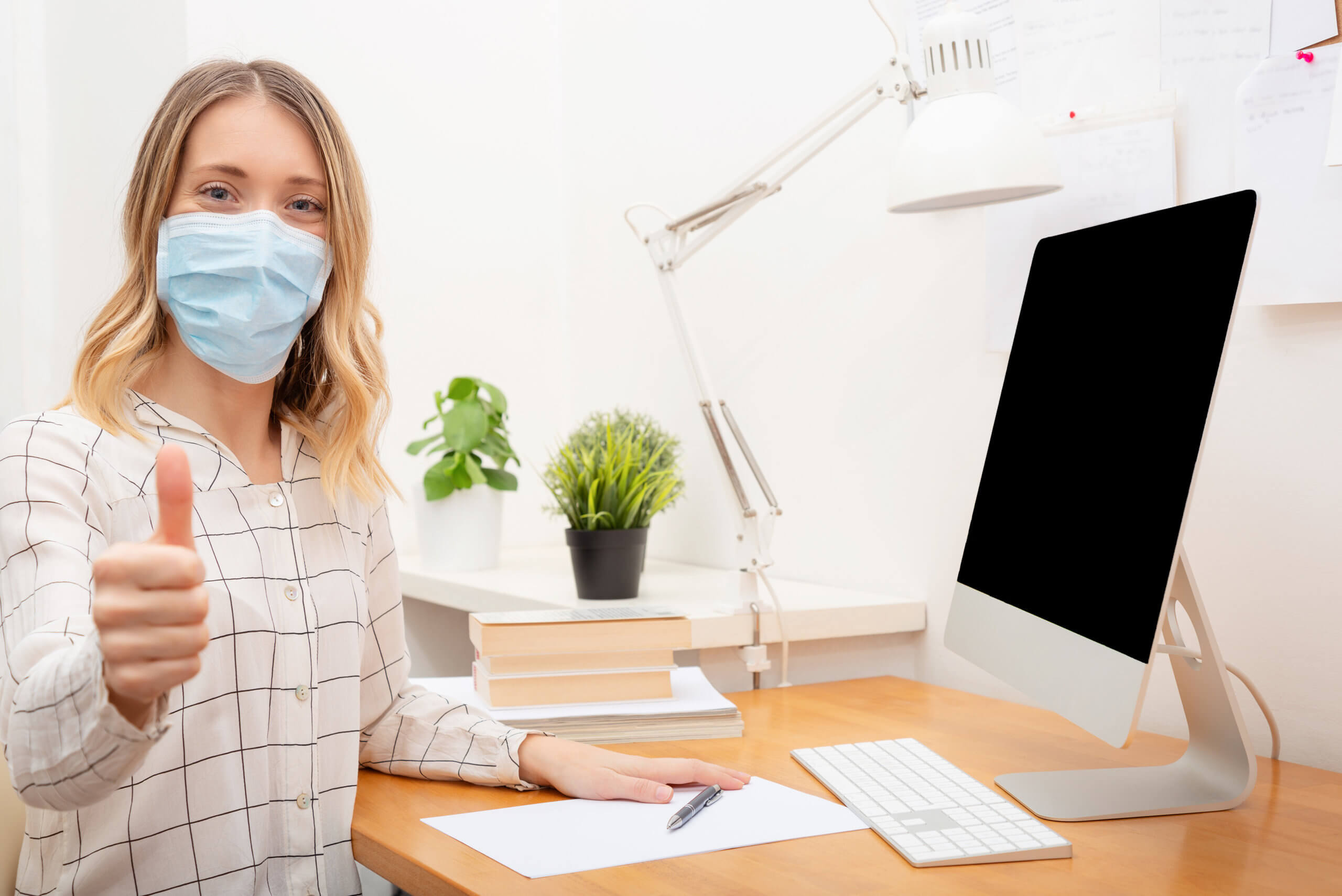 Young business woman working from home, wearing protective mask